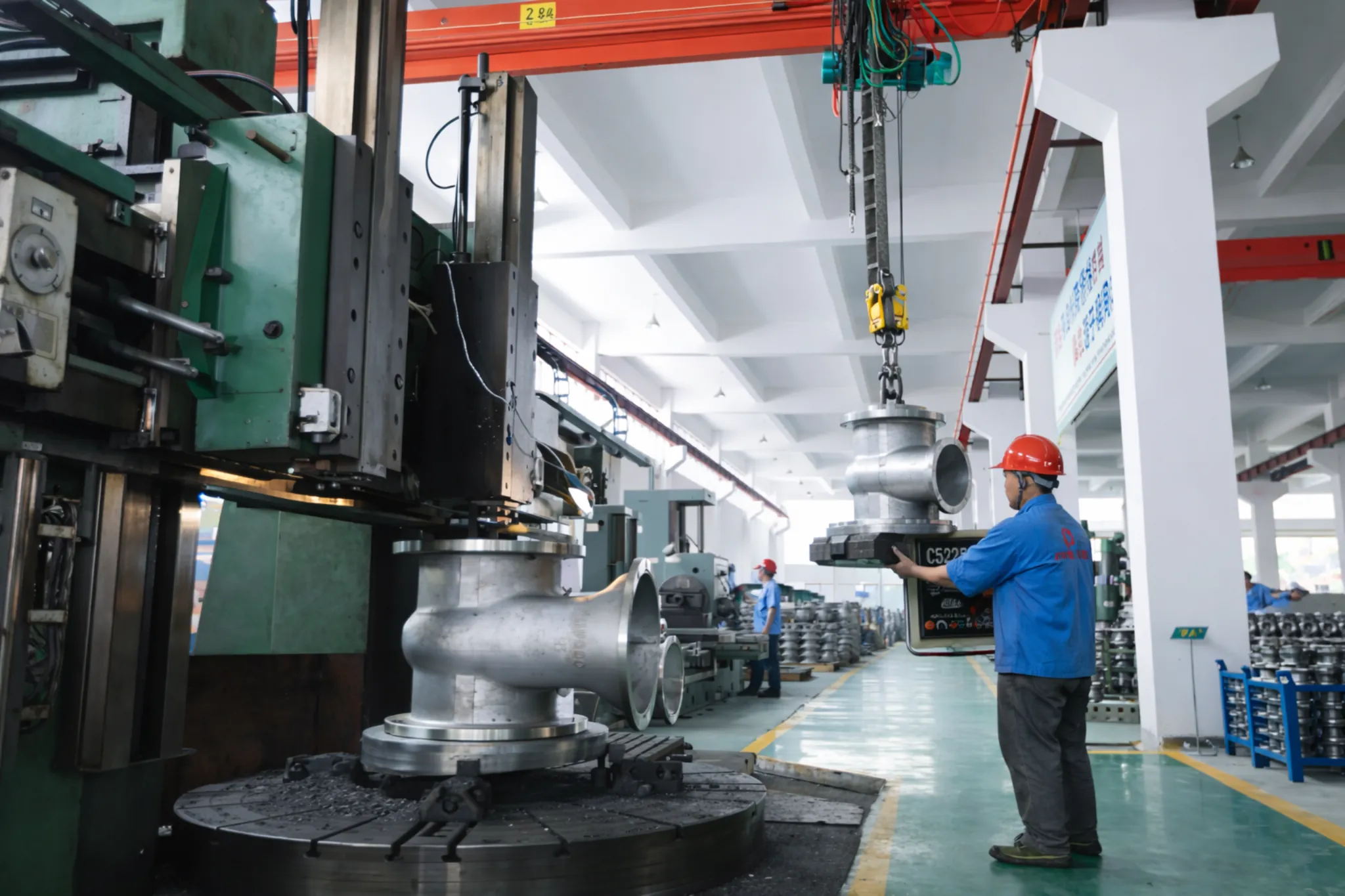 Workshop workers operating cranes to handle valves